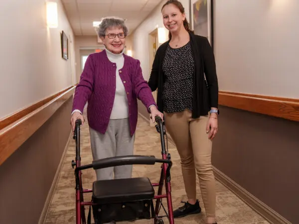 An employee standing next to a resident at United Zion Retirement Community