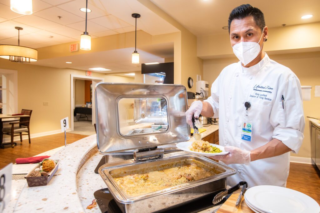 A member of the cooking staff preparing a meal for residents at United Zion Retirement Community